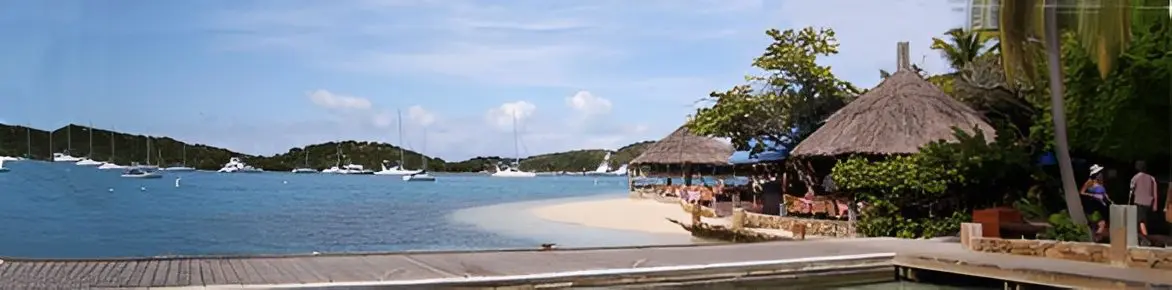 Tropical beach with anchored sailboats and huts